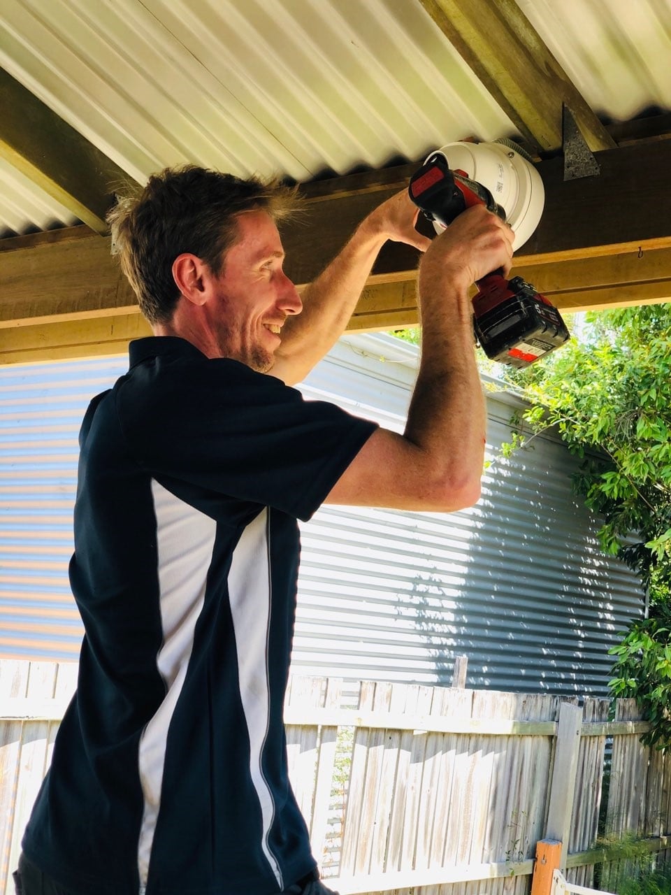 Fully Wired technician installing a security camera under the eave of a Brisbane home