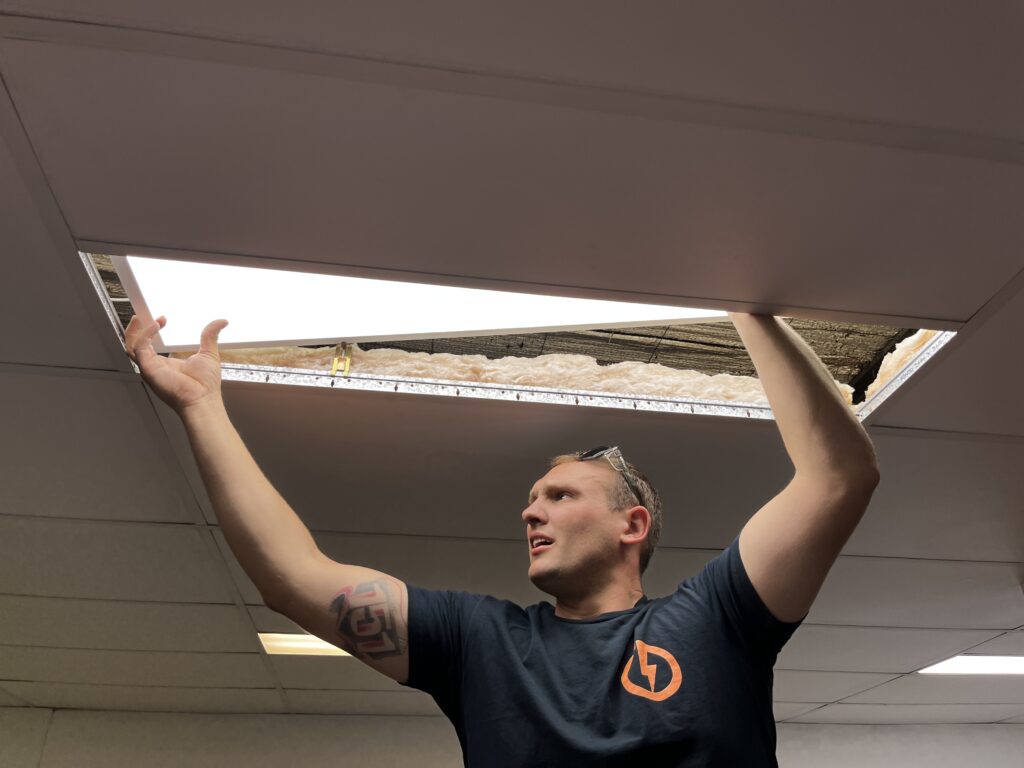 Electrician installing slim LED panel lights in a Brisbane office