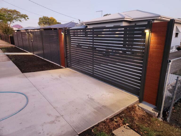Feature lighting installed along a modern front fence at dusk