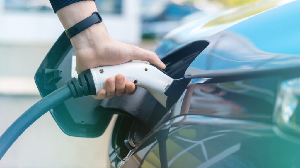 Hand plugging a charging cable into an electric vehicle charge port