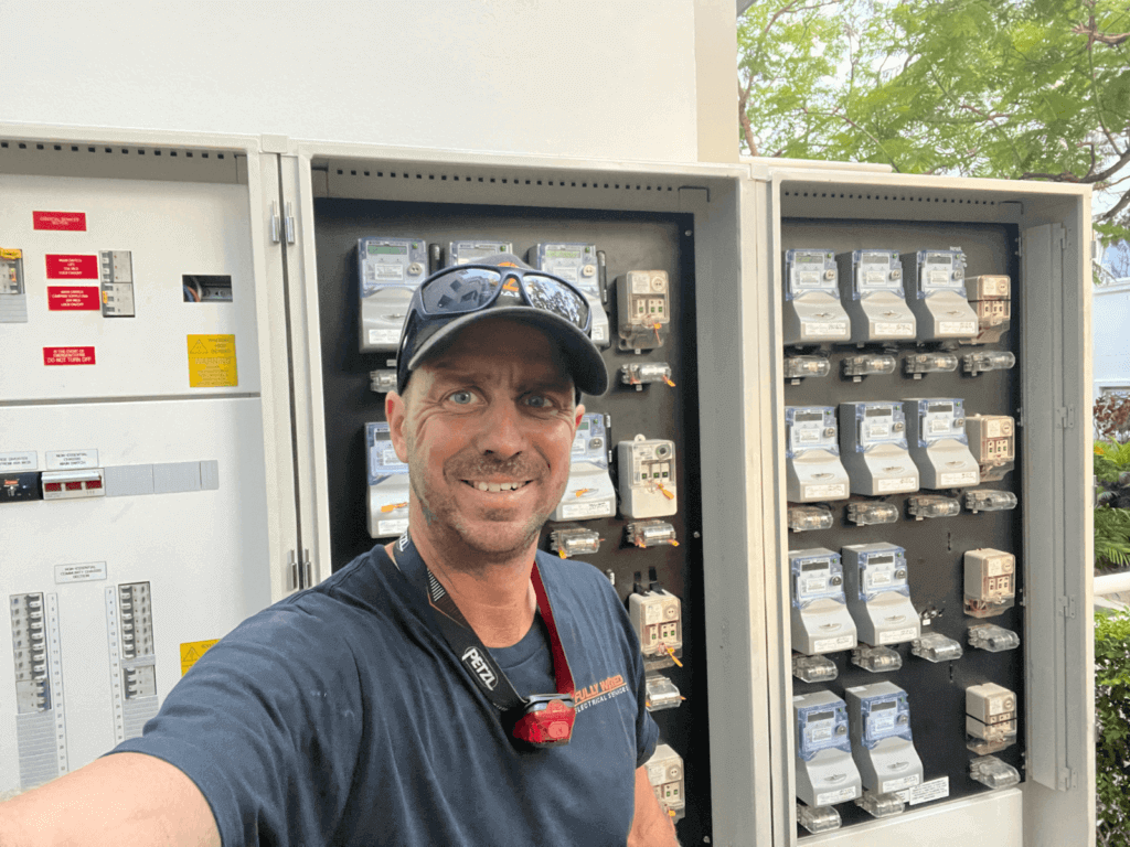 Fully Wired electrician beside newly installed main switchboards at an apartment block