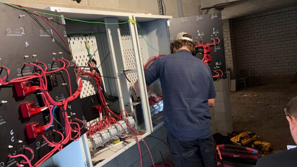 Electrician working on a unit building switchboard during a compliance upgrade in Taringa