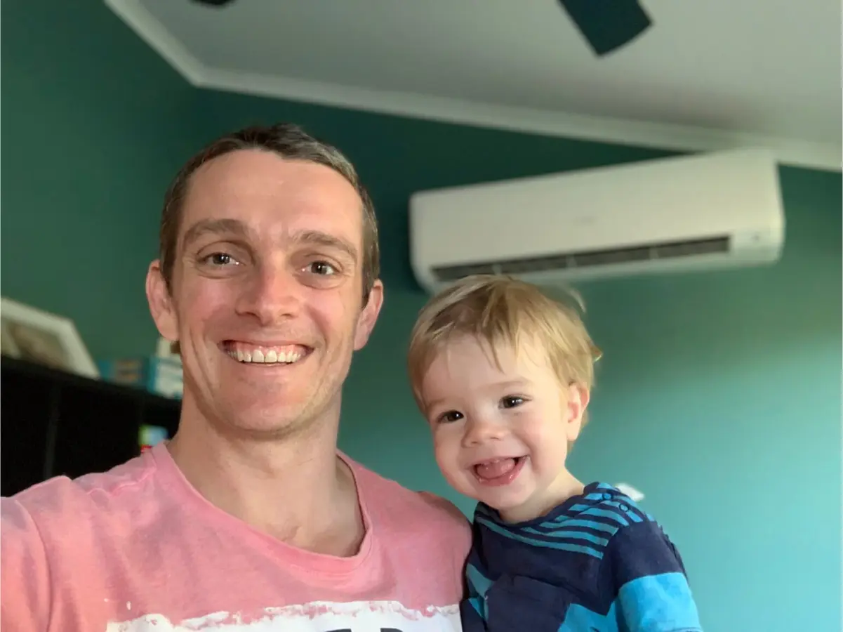 Happy Brisbane homeowner and child relaxing under a newly installed split system air conditioner