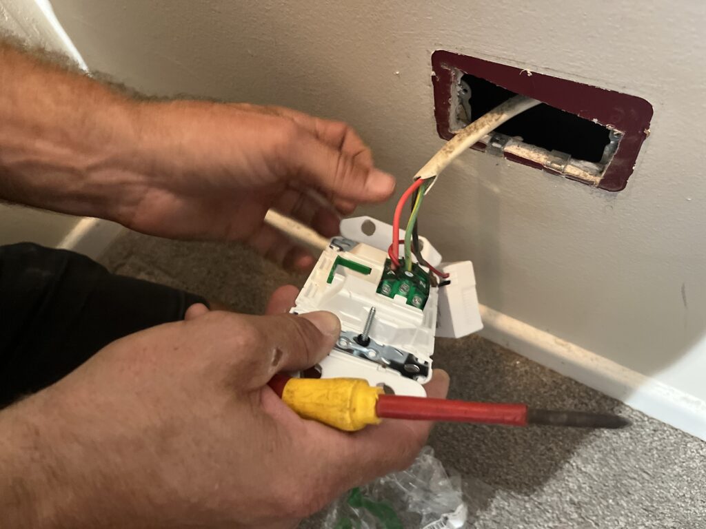 Electrician replacing an old power point with a modern switched socket