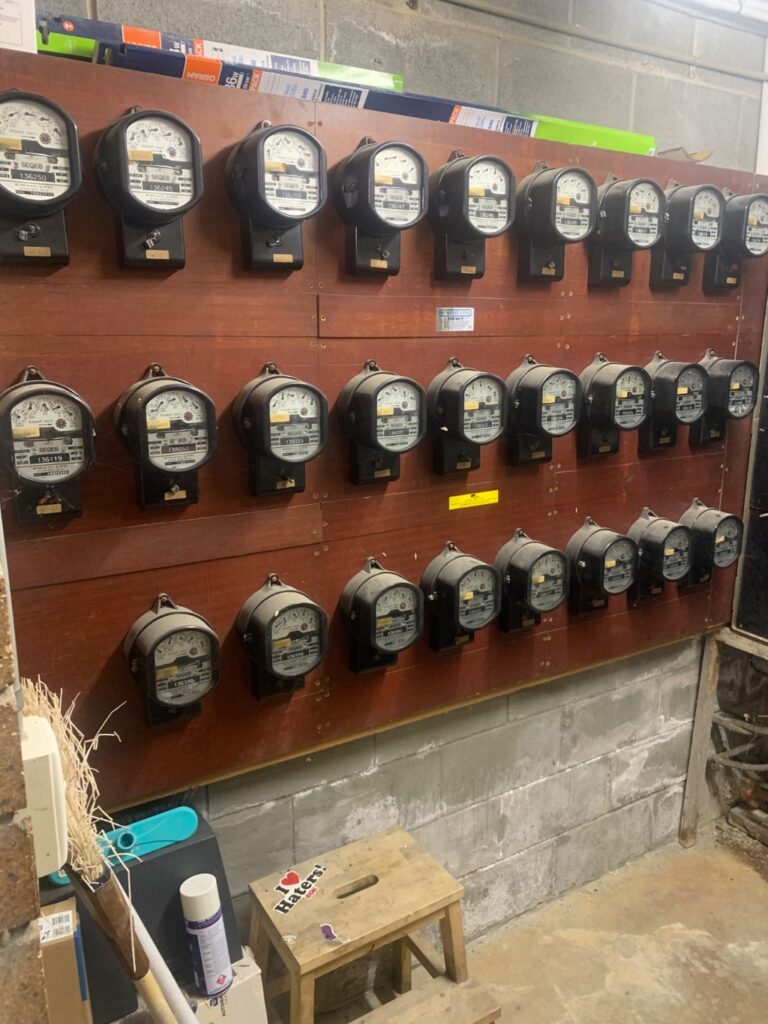 Rows of original spinning-disc meters on a timber panel at a Toowong apartment complex