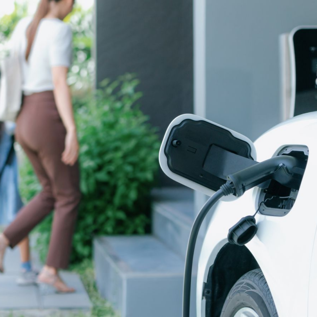 Driver walking past an electric car charging from a wall charger at a Brisbane home